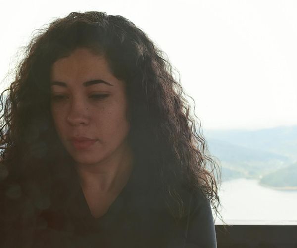 Person meditating outdoors with a serene landscape background.